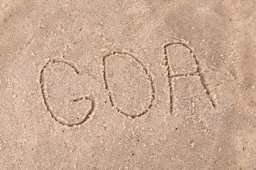 Inscription Goa in wet sand close-up background