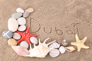 Fototapeta na wymiar Inscription Dubai in wet sand close-up background
