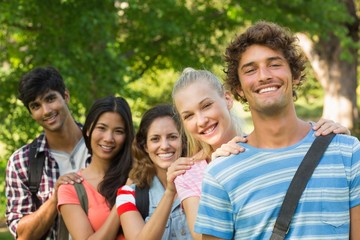 Happy college friends standing in row at campus