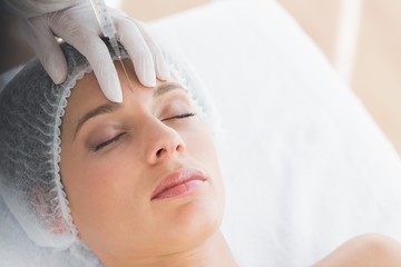 Fototapeta na wymiar Woman recieving botox injection in forehead