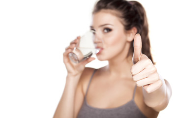beautiful woman drinks water from a glass and showing thumbs up