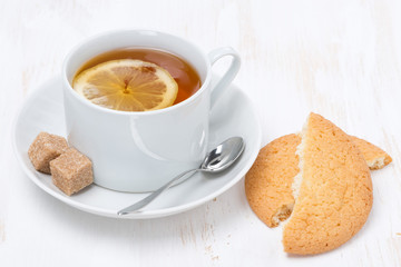 black tea with lemon and cookies on white wooden table