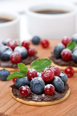 cake with chocolate cream and fresh berries on a wooden board