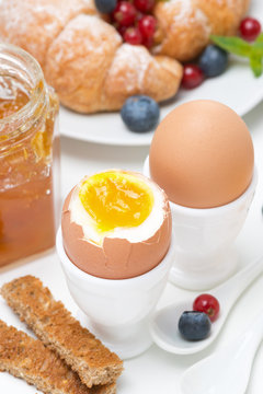 breakfast with eggs, toasts, croissants, fresh berries, close-up