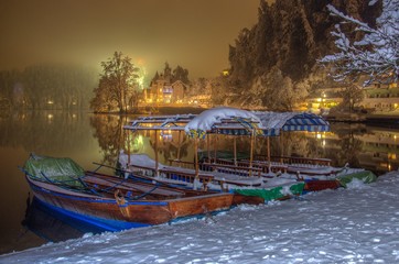 Pletna boats on the bank of Lake Bled in Winter snowy night