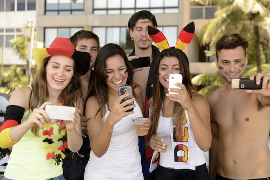 Group of happy German soccer fans holding smartphones