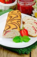Roulade with jam and strawberries on a board