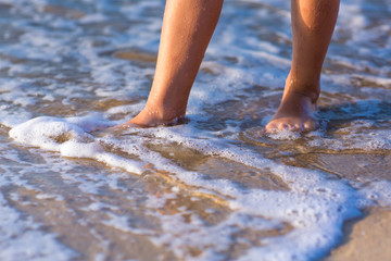Child walking with bare feet along the seashore