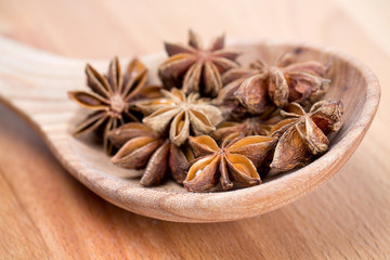 star anise in a spoon on wooden surface