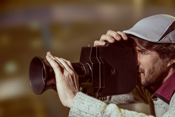 A man wearing a cap with an old movie camera