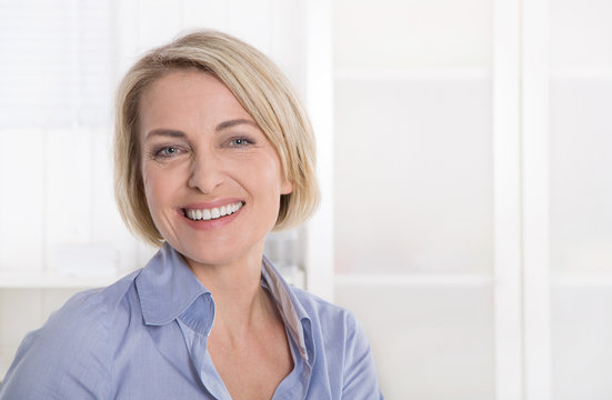 Ältere schöne blonde Frau - Portrait mit Hintergrund weiß blau