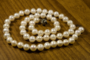 pearl necklace on wood background
