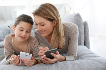 Mother and daughter playing games with smartphone