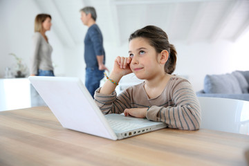 Young girl at home trying to do homework on laptop