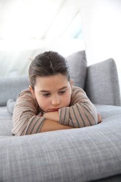 Portrait Of Sad Little Girl Laying On Couch