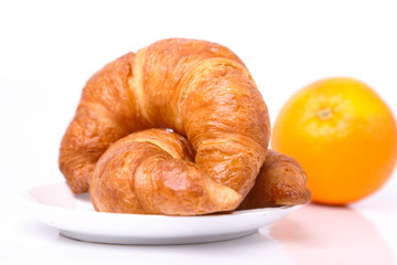 Croissants and an orange on the background