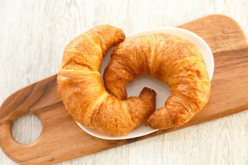 Two croissants on a plate and a wooden board