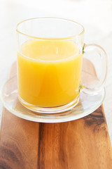 A mug of orage juice on a wooden board