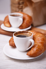 Two cups of coffee and croissants next to them