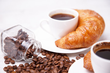 A white cup of coffee and croissants