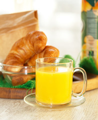 Orange juice in a transparent mug with pastries on the backgroun
