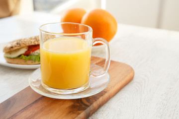 A mug of orange juice on a chopping board