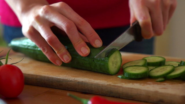 Woman slicing cucumber on chopping board