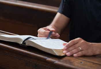 Man reading Bible in a church.