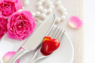 Romantic table setting with pink roses on a linen napkin