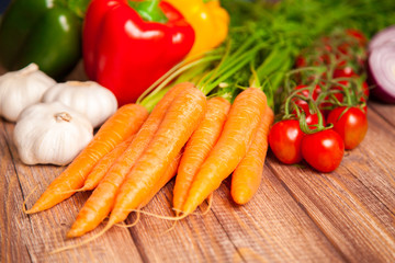 Carrot, tomato and paprika on a wooden table