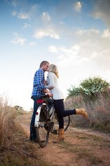 Young adult couple with old bicycle kissing