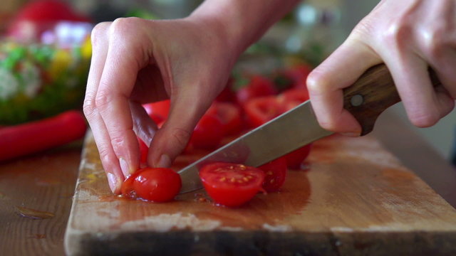Slicing cherry tomatoes on chopping board