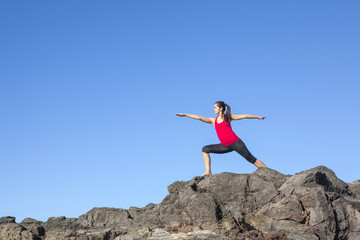 Obraz premium Young woman practicing yoga warrior pose outdoor