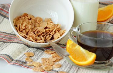 Flakes in a deep plate, cup of coffee and orange, sliced