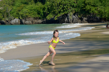 Happy girl plays in sea on tropical beach