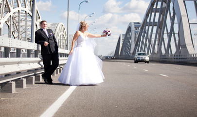 Obraz premium Newly married couple hitchhiking on road
