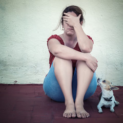 Sad woman crying with a small dog besides her