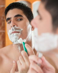 Young hispanic man shaving