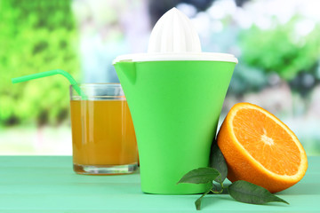 Citrus press, glass of juice and ripe orange