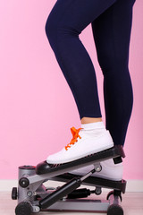 Woman doing exercise on stepper. Close-up on legs.