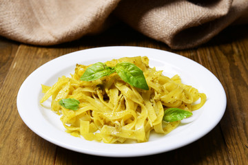 Delicious pasta with pesto on plate on table close-up