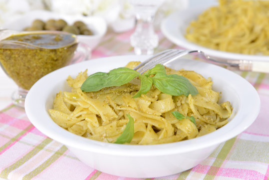 Delicious pasta with pesto on plate on table on light