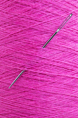 long stainless needle stuck in purple wool texture thread