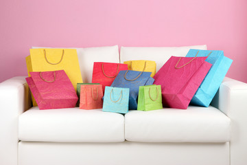 Colorful shopping bags on sofa, on color wall background