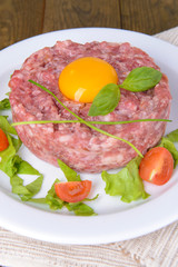 Delicious steak tartare with yolk on plate on table close-up