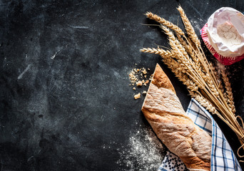 Rustic baguette, wheat and flour on black chalkboard