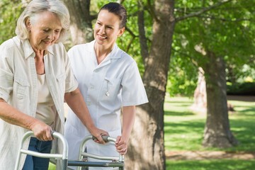 Female assisting mature woman with walker at park