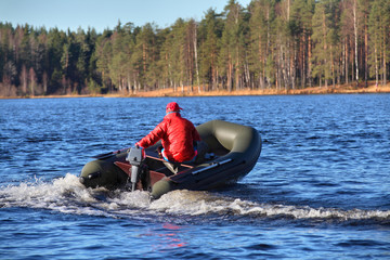 Dark green, inflatable rubber dinghy boat with motor, forest Lak