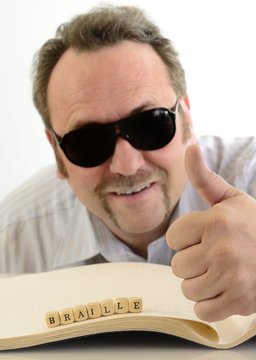 Mann mit Holzw&uuml;rfel und Blindenschrift