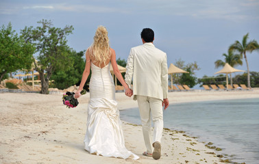 Fototapeta na wymiar Bride and groom walking together on beach